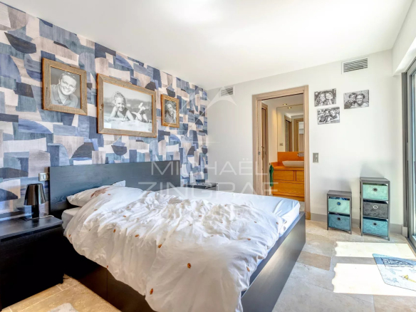 Bedroom with blue geometric wallpaper, a low dark bed, white duvet, and framed photos on the wall above the headboard.