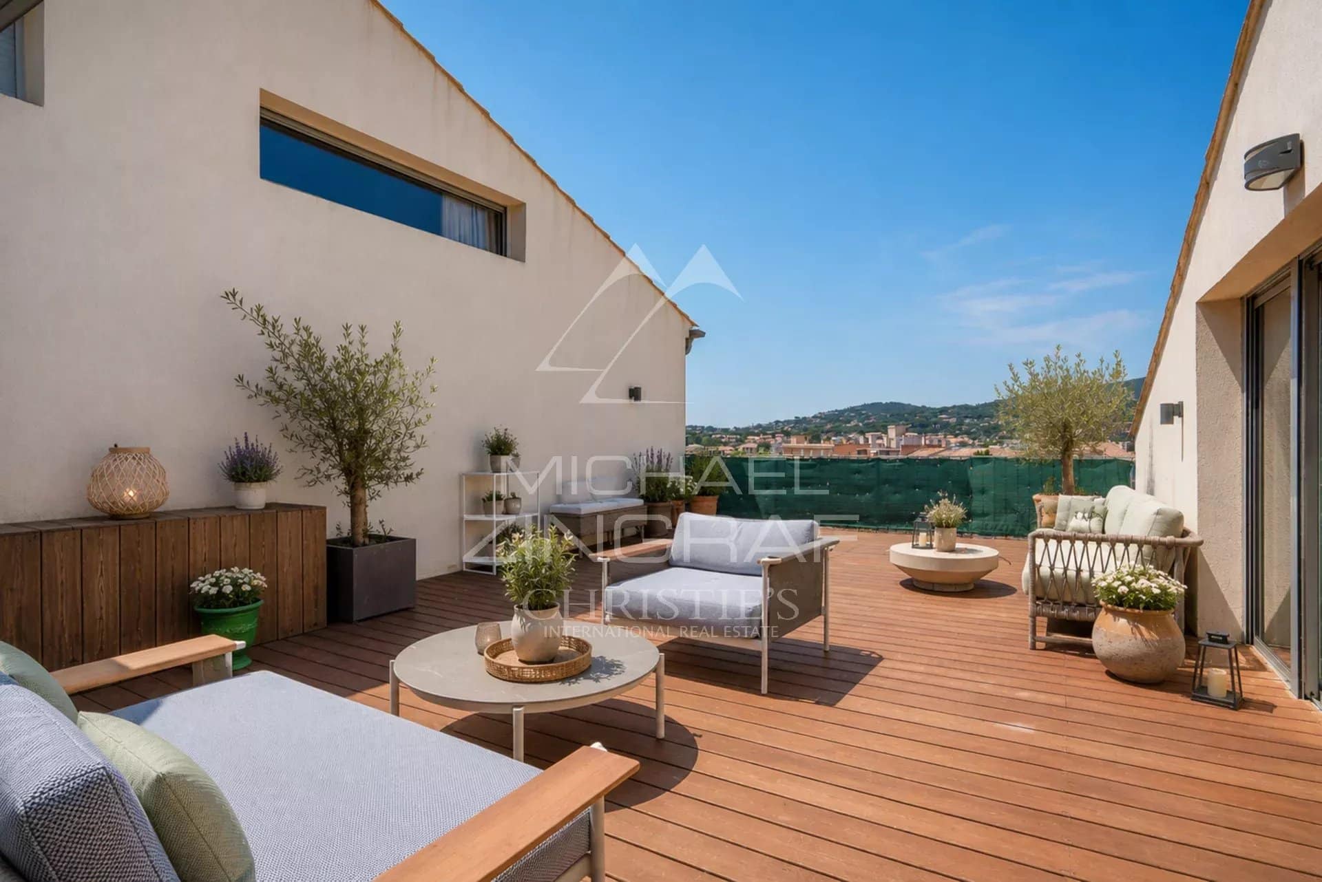 Terrasse d’un appartement à Sainte-Maxime Terrasse en bois avec mobilier moderne à Sainte-Maxime, vue sur la ville et la nature environnante.