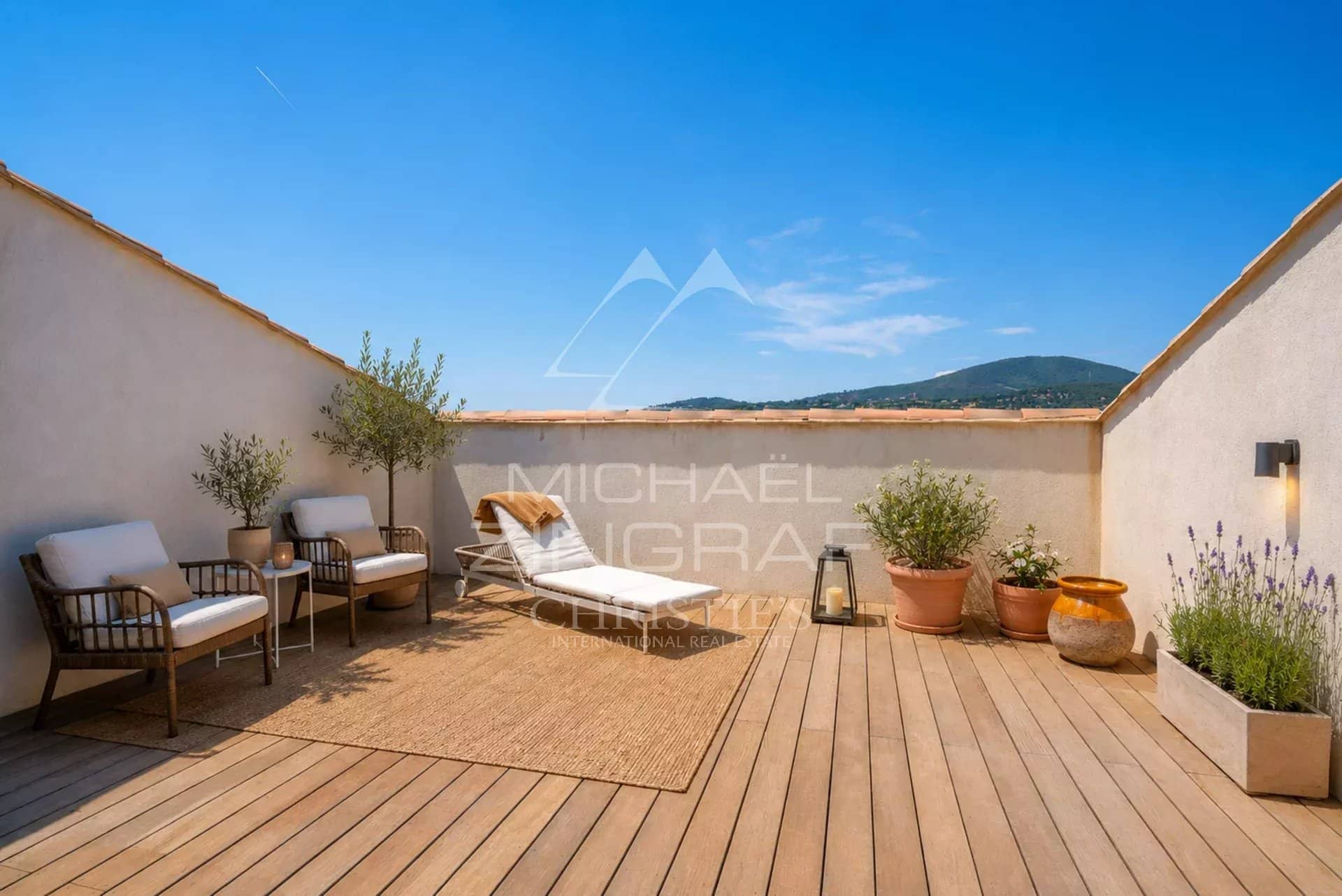 Terrasse d’un appartement à Sainte-Maxime Terrasse en bois avec chaises et plantes, vue dégagée sur la montagne à Sainte-Maxime.