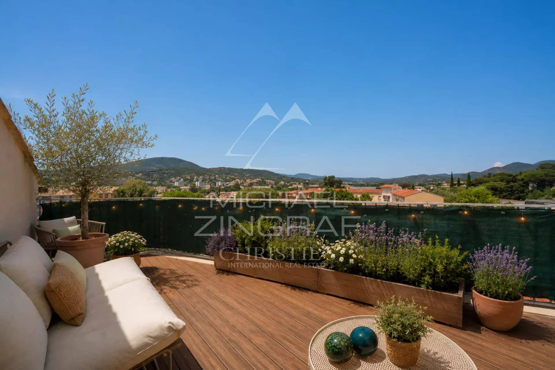 Terrasse d’un appartement d’exception à Sainte-Maxime Terrasse d'un appartement à Sainte-Maxime avec vue sur les collines et la végétation environnante.