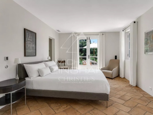 Chambre d'une villa provençale à Ramatuelle, avec un lit double et des fenêtres donnant sur le jardin.