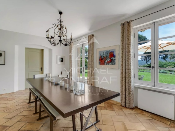 Intérieur d'une villa provençale à Ramatuelle avec une grande table à manger et des fenêtres donnant sur le jardin.