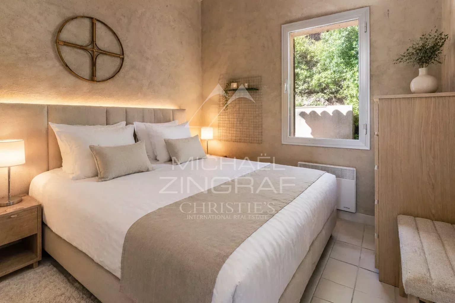 Chambre d'une maison rénovée avec murs en stuc et fenêtre donnant sur l'extérieur.
