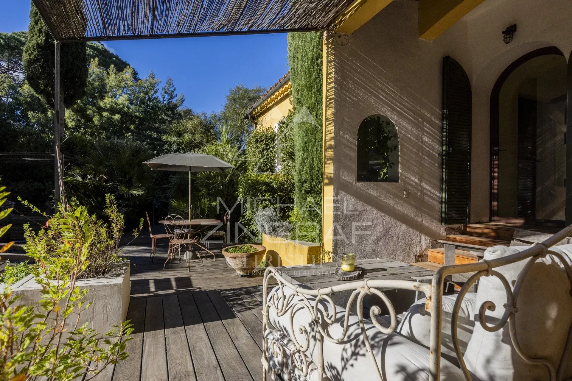 Terrasse d'un appartement rénové avec mobilier de jardin et parasol, entourée de verdure à Gassin.