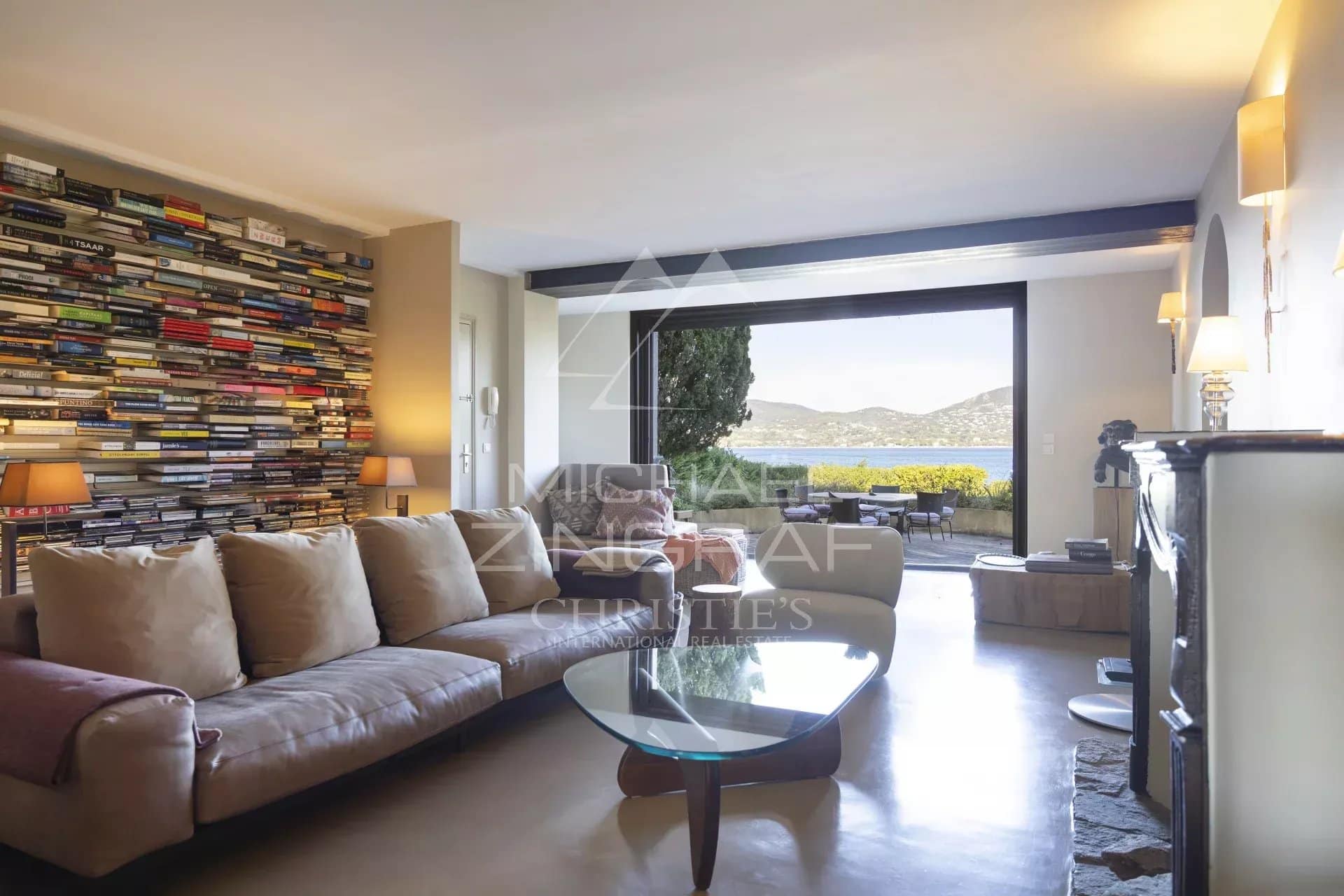 Salon d'un appartement rénové avec vue sur la mer à Gassin, murs décorés de livres.