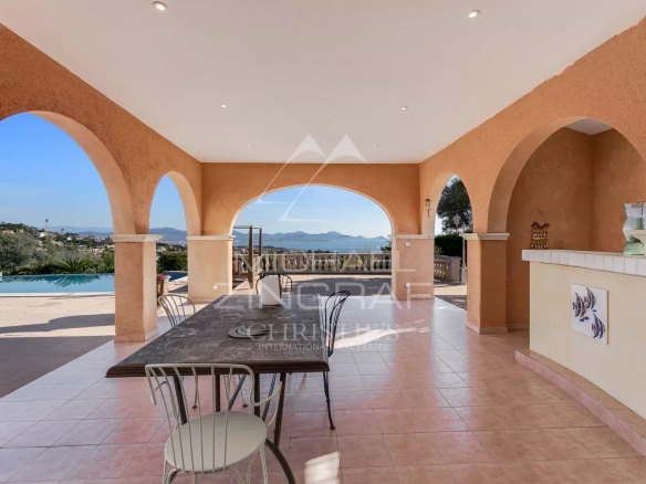 Terrasse d'une villa avec vue sur la mer, entourée de colonnes et d'une table en extérieur