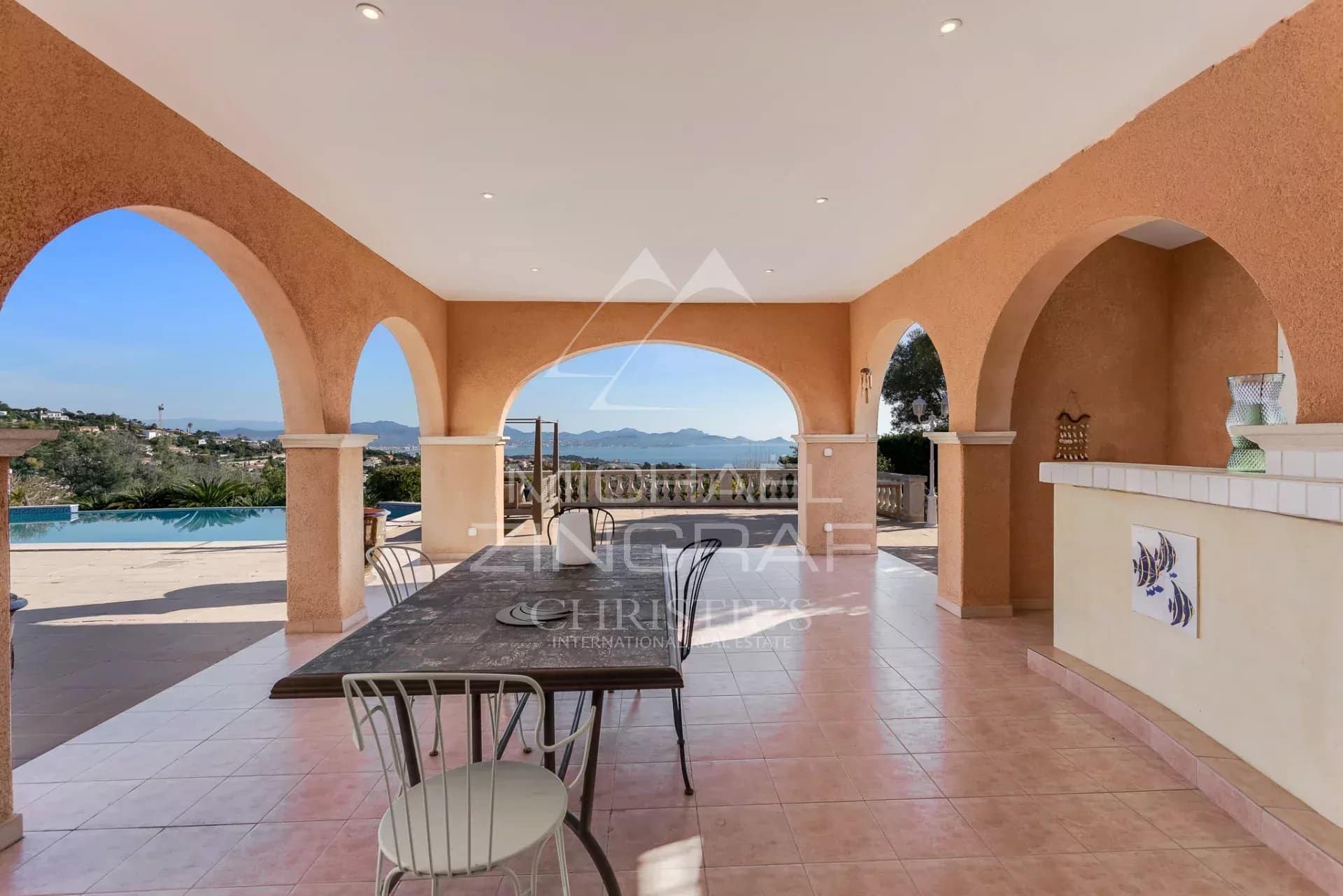 Terrasse d'une villa avec vue sur la mer, entourée de colonnes et d'une table en extérieur
