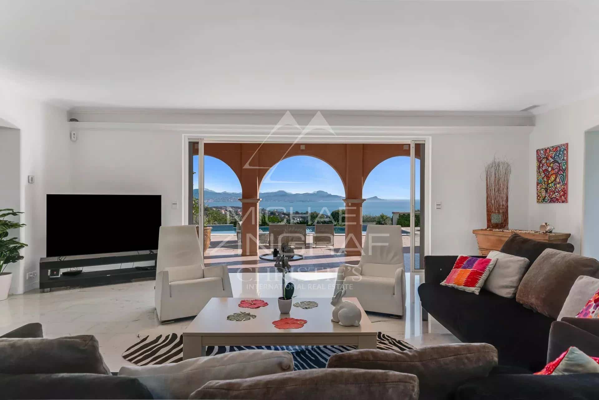 Intérieur d'une villa avec vue panoramique sur la mer, salon lumineux et moderne.