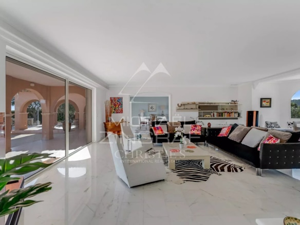 Intérieur d'une villa moderne avec vue sur la mer, mobilier contemporain et lumière naturelle.