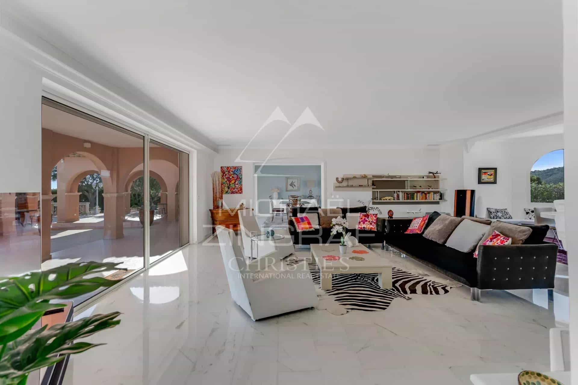 Intérieur d'une villa moderne avec vue sur la mer, mobilier contemporain et lumière naturelle.