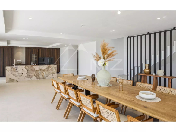 Interior of a contemporary villa with a large wooden table and a modern kitchen in Les Issambres.