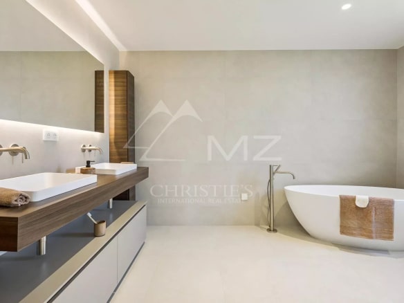 Modern bathroom with bathtub and double sink, minimalist decor.