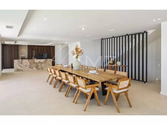 Interior of a contemporary villa with a large dining table and an open kitchen.