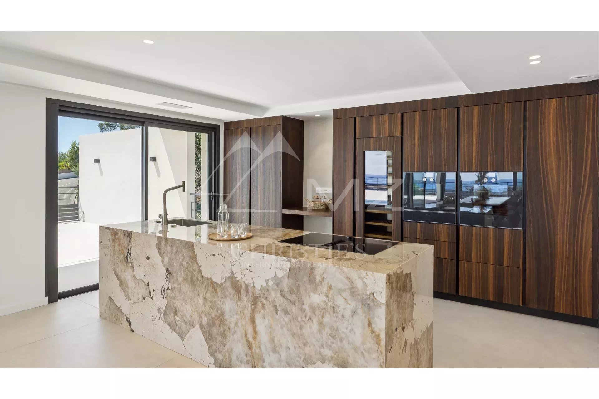 Contemporary cuisine in Les Issambres Modern kitchen with a stone island and wooden storage, sea view.