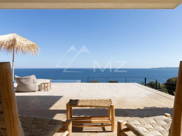 View from a terrace with wooden chairs and a parasol, overlooking the Mediterranean Sea.