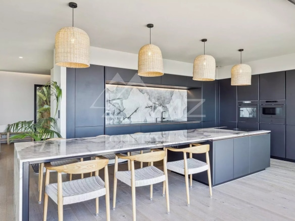 Modern kitchen in a contemporary villa with central island and wicker light fixtures.