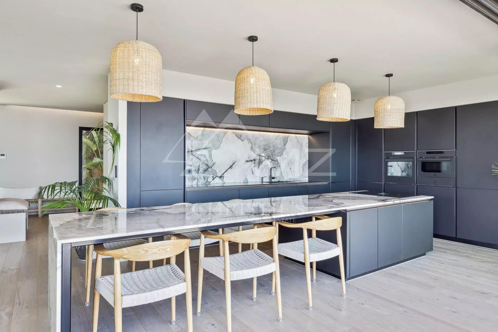 Modern kitchen in a contemporary villa with central island and wicker light fixtures.