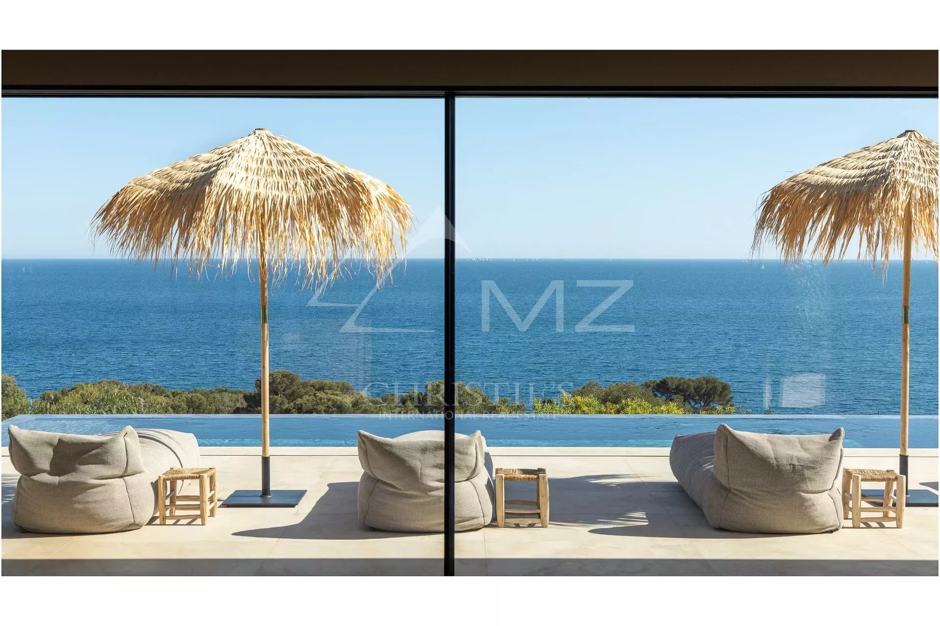 Sea view from a contemporary villa with parasols and sun loungers.