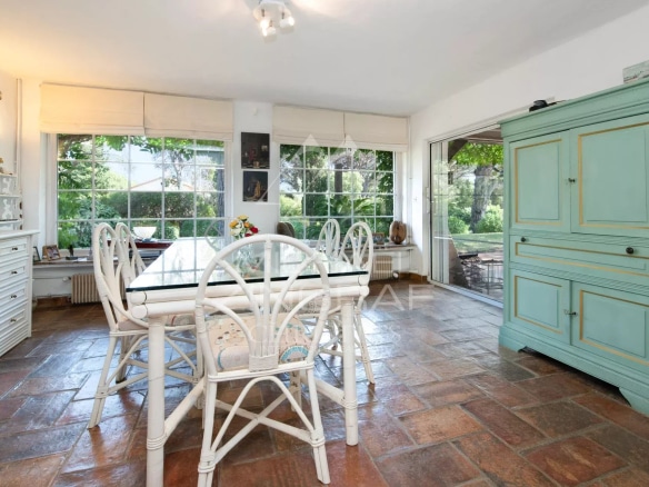 Intérieur d'une villa avec salle à manger lumineuse et vue sur un jardin paysager.