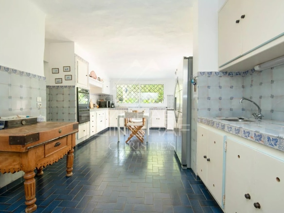 Intérieur d'une cuisine spacieuse avec carrelage bleu et mobilier en bois dans une villa à Sainte-Maxime.