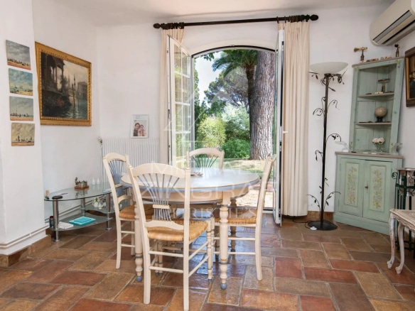 Salle à manger lumineuse avec vue sur le jardin, décorée de meubles en bois et d'œuvres d'art.