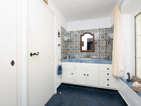 Salle de bain avec carrelage bleu et décorations murales colorées dans une villa à Sainte-Maxime.