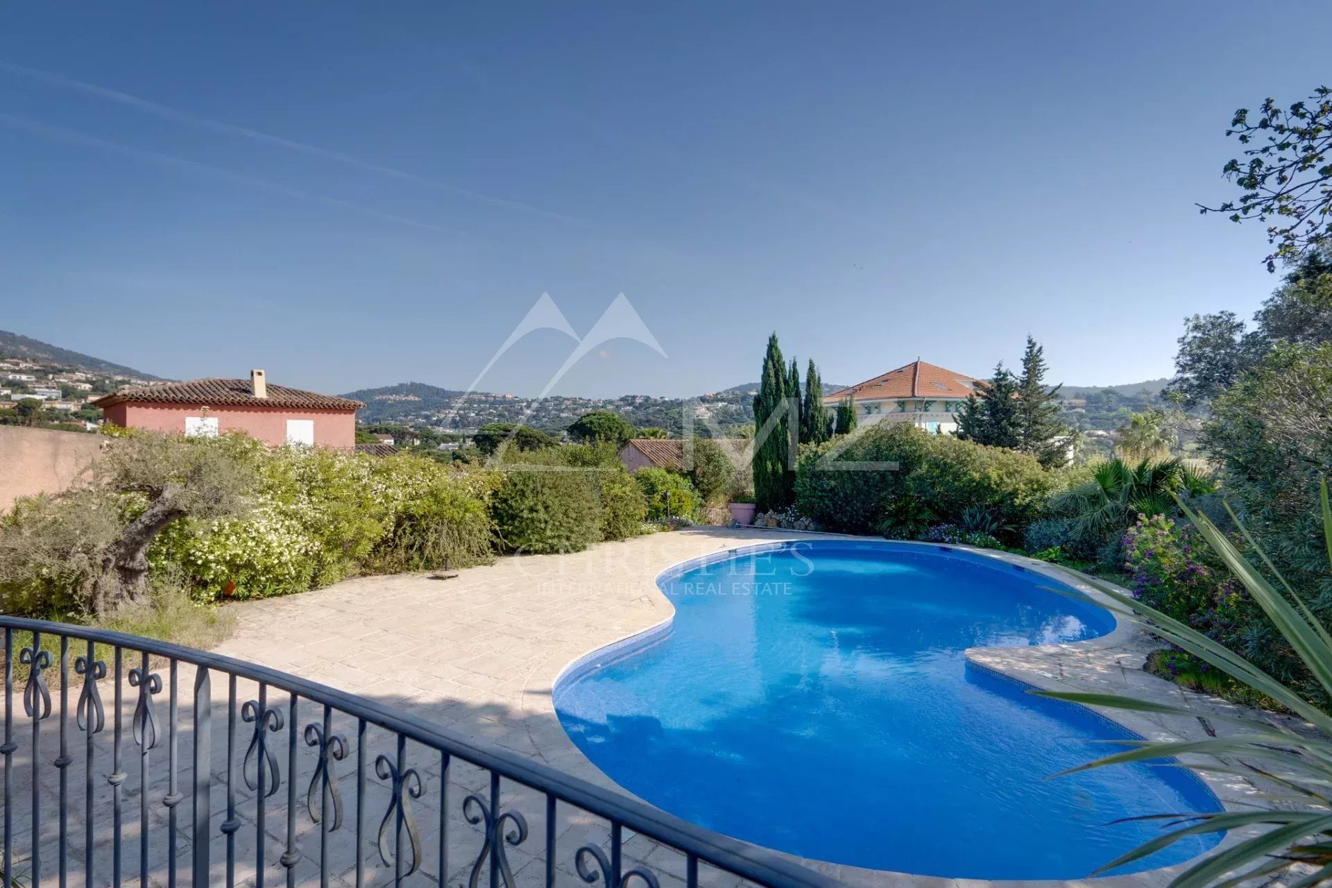 Vue d'une piscine dans une propriété à Sainte-Maxime, avec des jardins et des maisons environnantes.