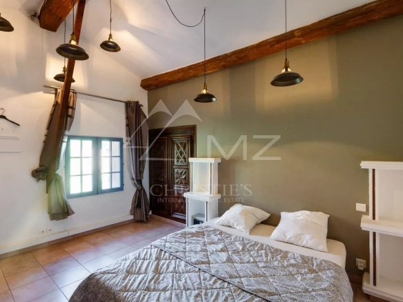 Chambre d'une propriété à Sainte-Maxime avec lit et fenêtres, décor méditerranéen.