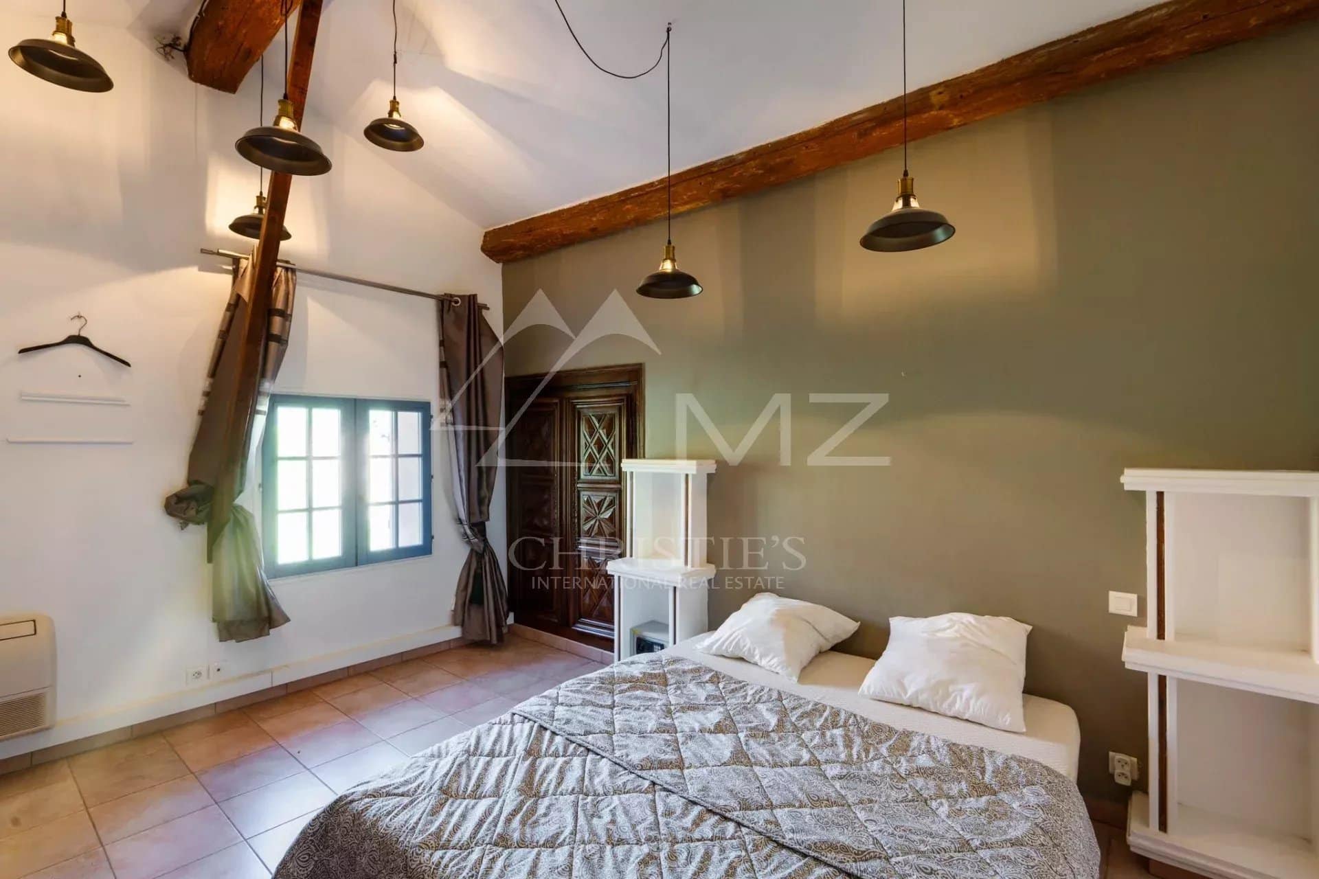Chambre d'une propriété à Sainte-Maxime avec lit et fenêtres, décor méditerranéen.