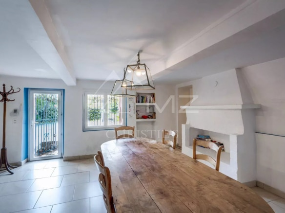 Intérieur d'une propriété à Sainte-Maxime avec une grande table en bois et des fenêtres donnant sur l'extérieur.