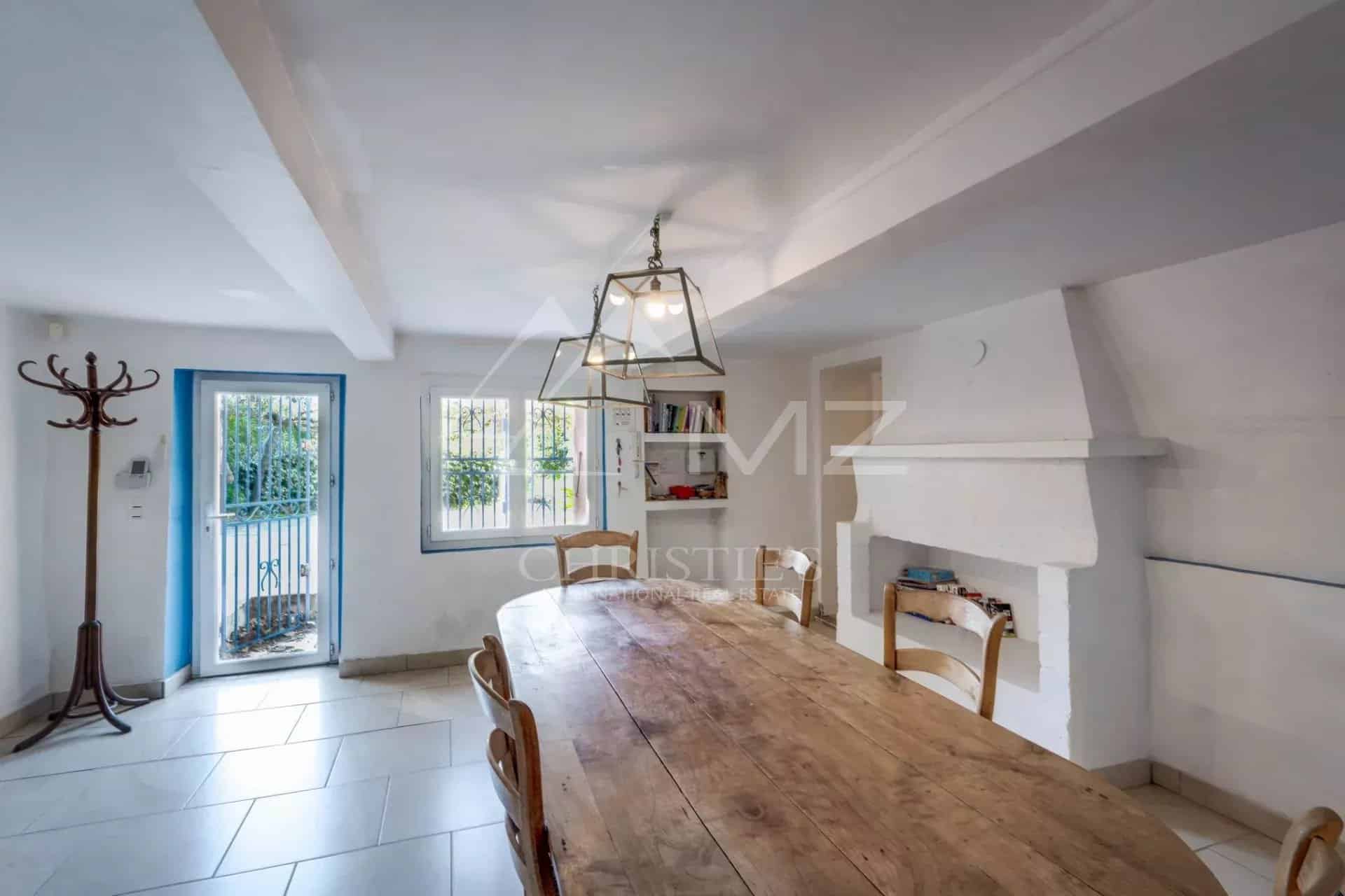 Intérieur d'une propriété à Sainte-Maxime avec une grande table en bois et des fenêtres donnant sur l'extérieur.