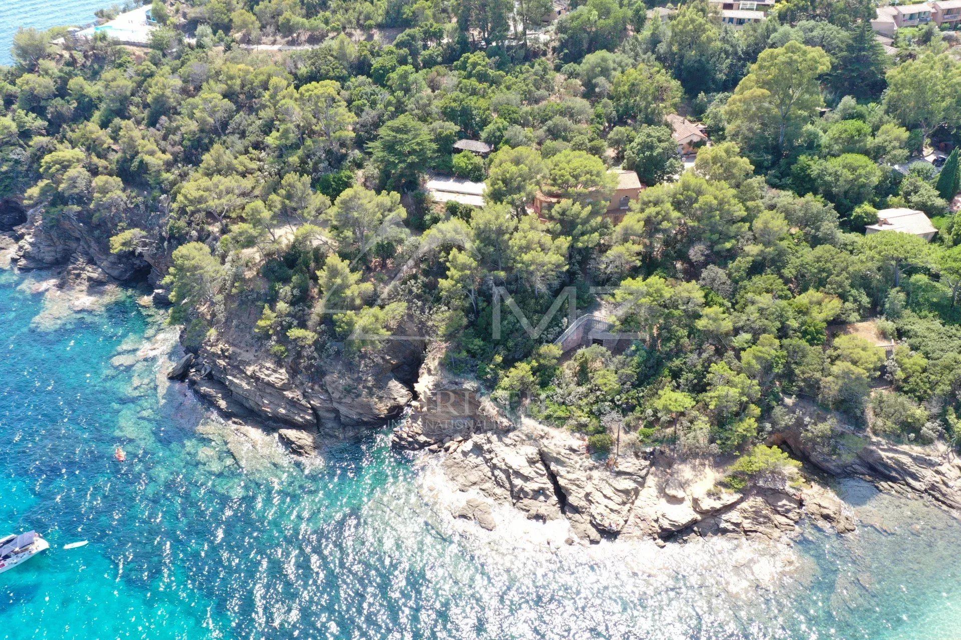 Vue aérienne d'une propriété en bord de mer avec des arbres et des rochers au Lavandou.
