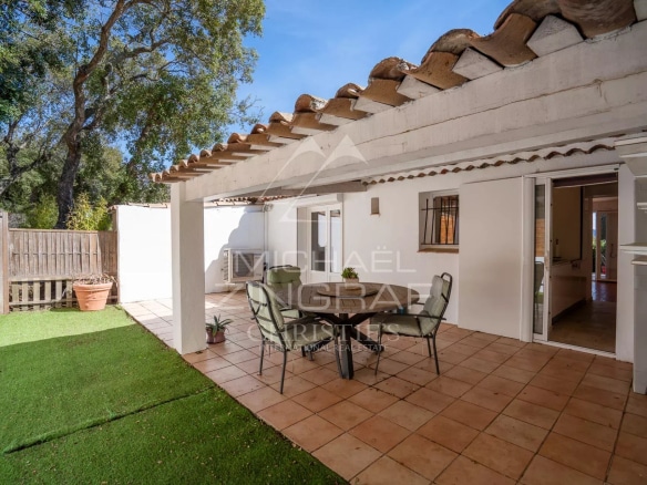 Terrasse d'une maison avec mobilier de jardin, vue sur un espace vert.