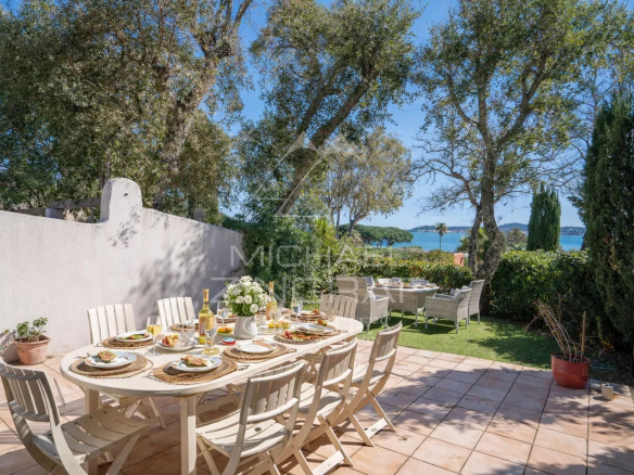 Terrasse d'une maison avec vue sur la mer, table dressée pour un repas en extérieur.