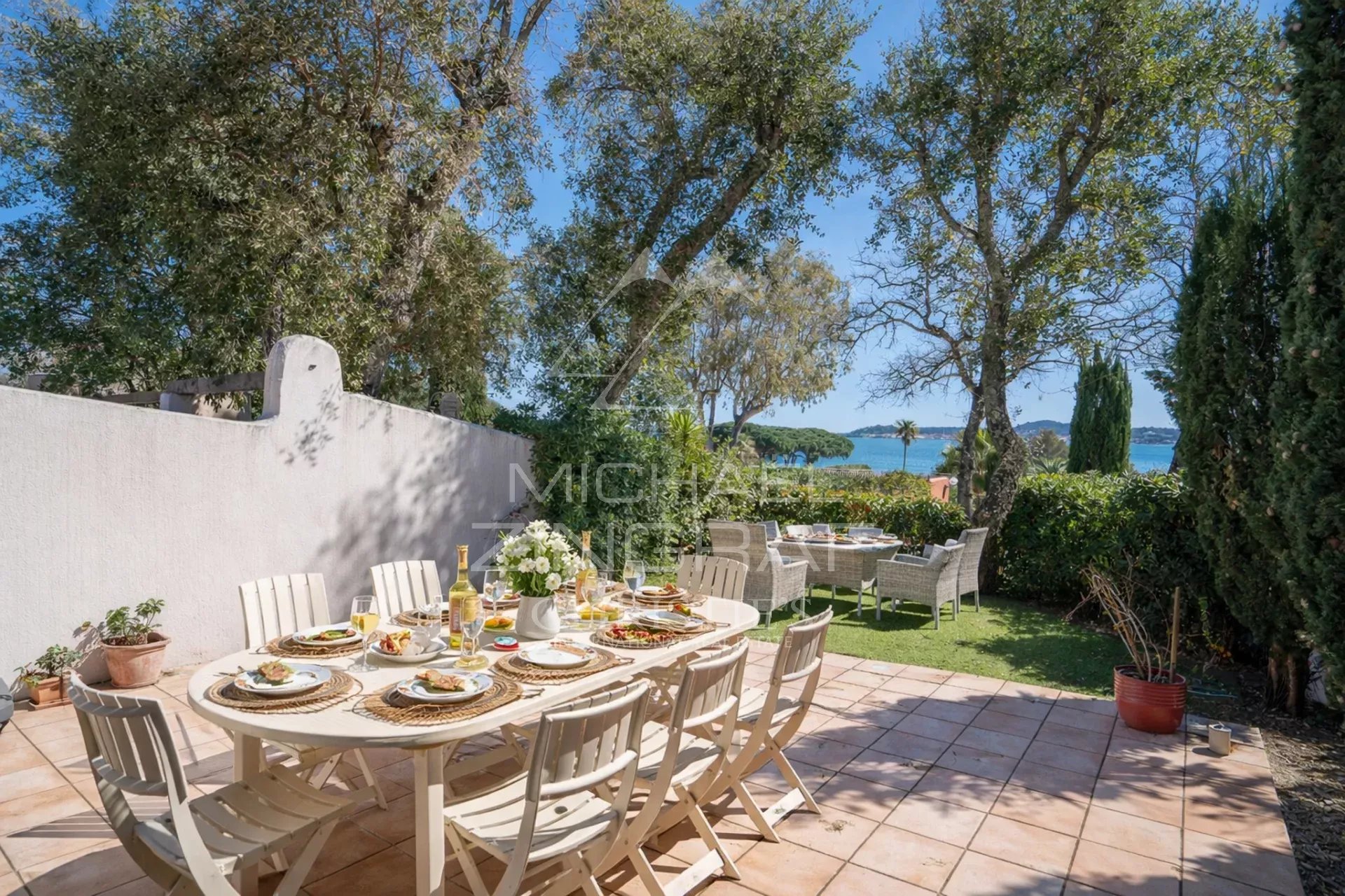 Terrasse d'une maison avec vue sur la mer, table dressée pour un repas en extérieur.