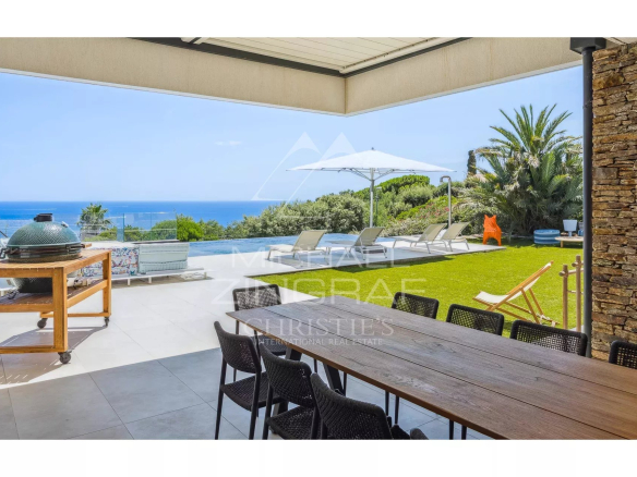Terrace of a contemporary villa with sea view, garden furniture and swimming pool.