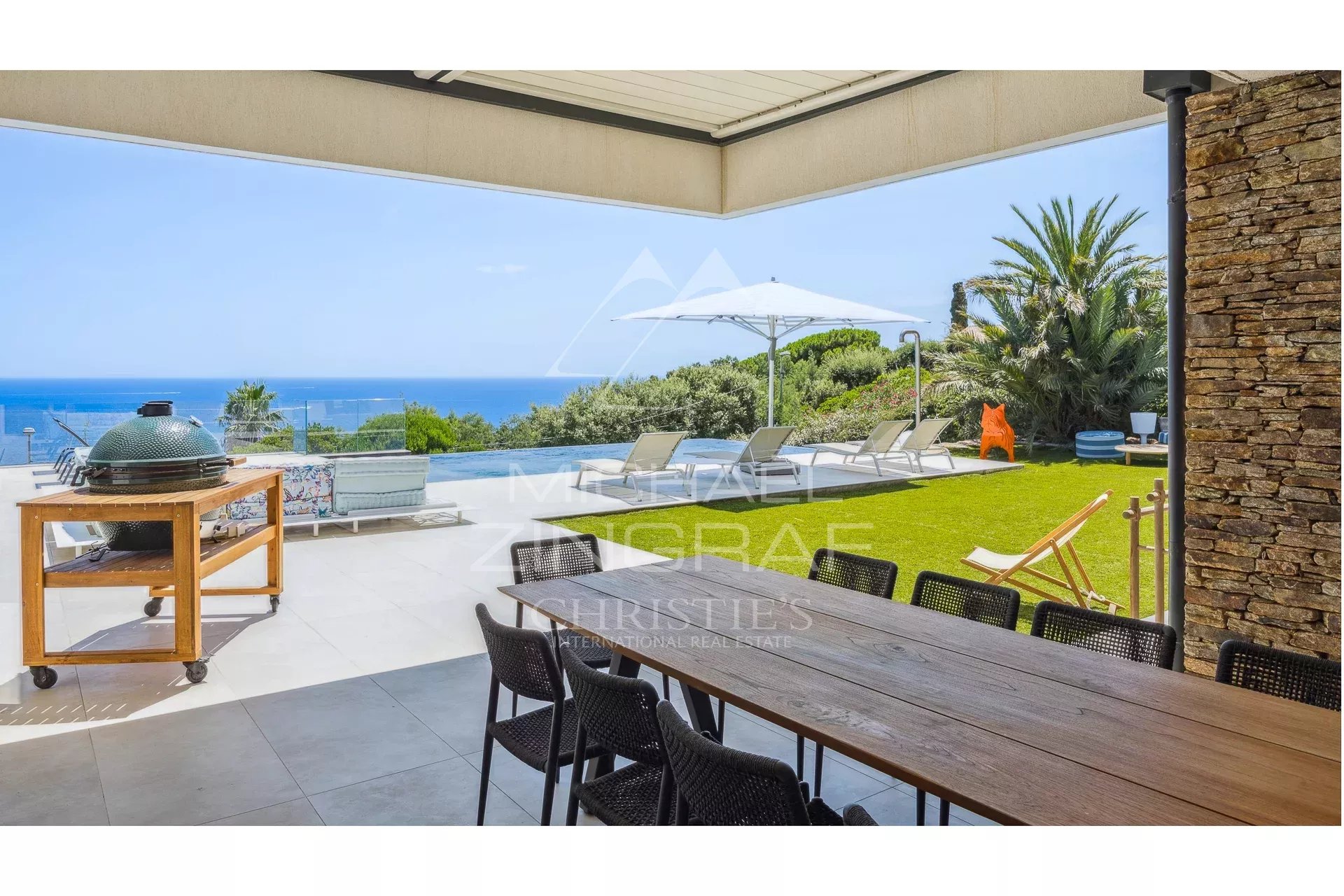 Terrace of a contemporary villa with sea view, garden furniture and swimming pool.