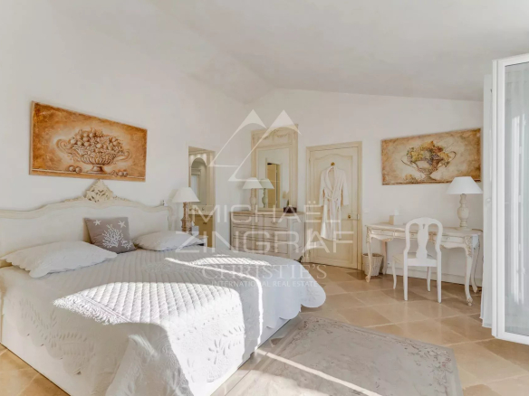 Chambre lumineuse d'une villa à Port Grimaud avec lit double et décoration élégante.