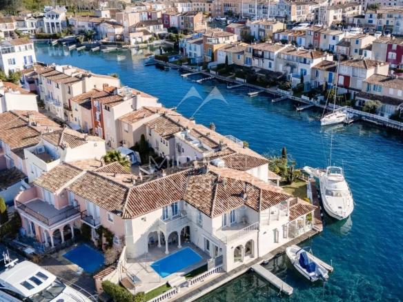 Vue aérienne d'une villa élégante avec piscine à Port Grimaud, entourée de canaux et de maisons colorées.