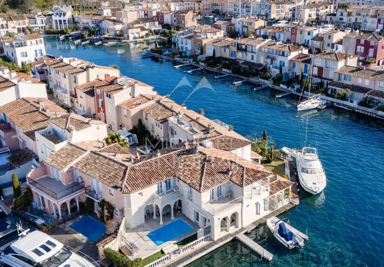 Villa élégante à Port Grimaud Vue aérienne d'une villa élégante avec piscine à Port Grimaud, entourée de canaux et de maisons colorées.