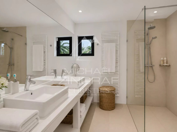 Salle de bain moderne avec douche et lavabo, décorée de manière épurée.