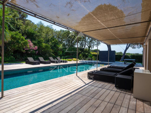 Terrasse avec piscine et chaises longues entourée de jardins à Saint-Tropez.