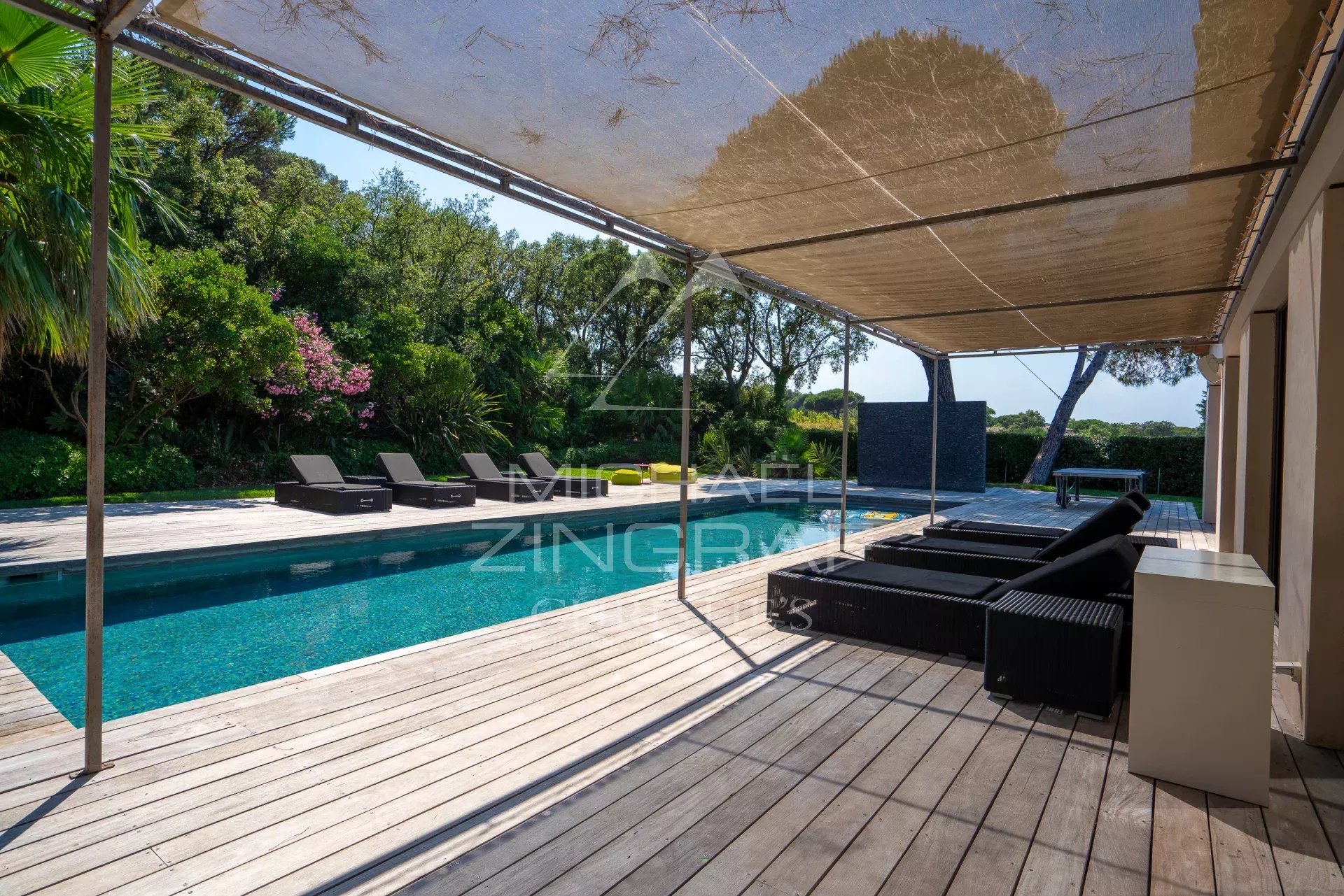 Terrasse et piscine à Saint-Tropez Terrasse avec piscine et chaises longues entourée de jardins à Saint-Tropez.