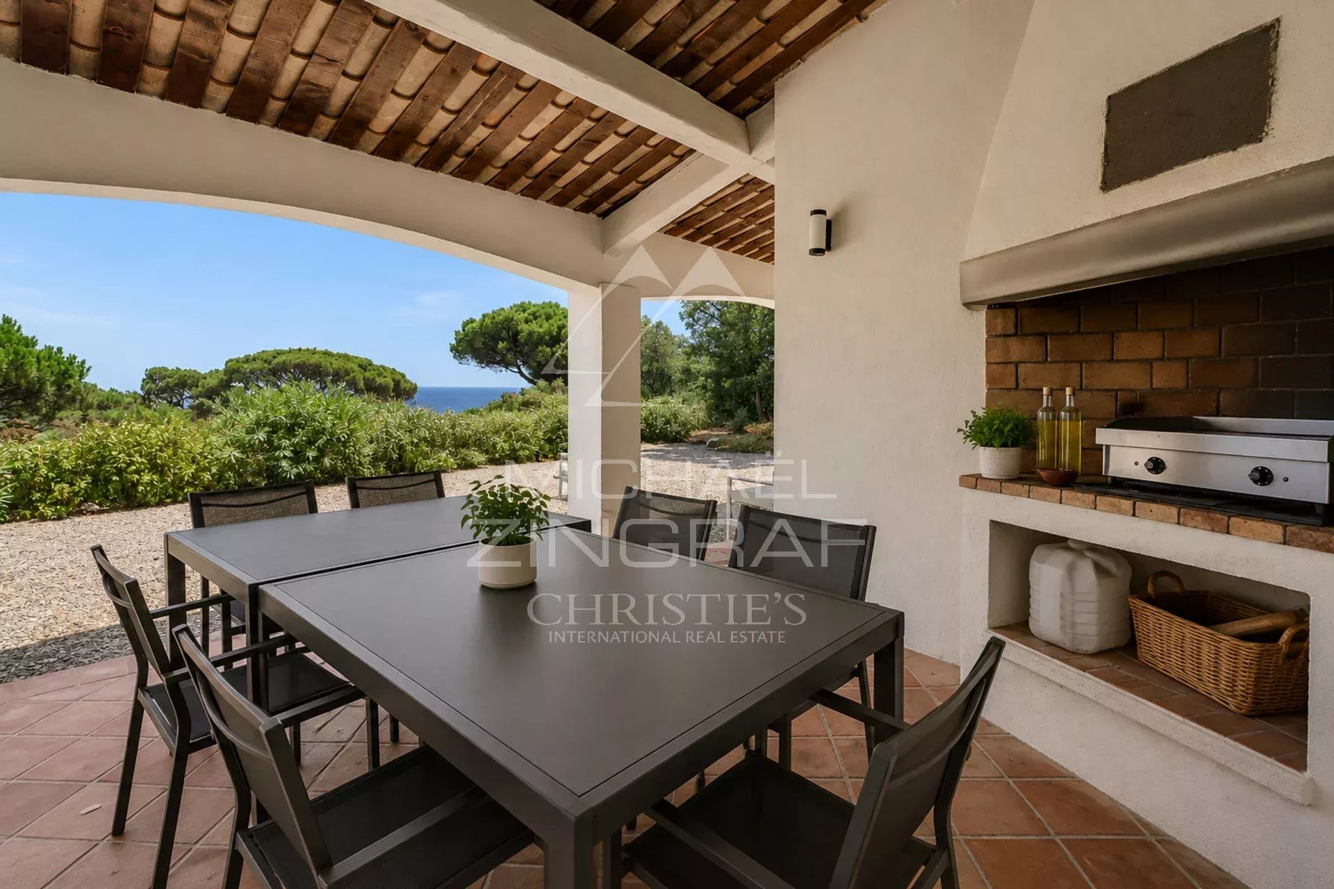 Terrasse d'une villa à Sainte-Maxime avec table et barbecue, vue sur la nature environnante.