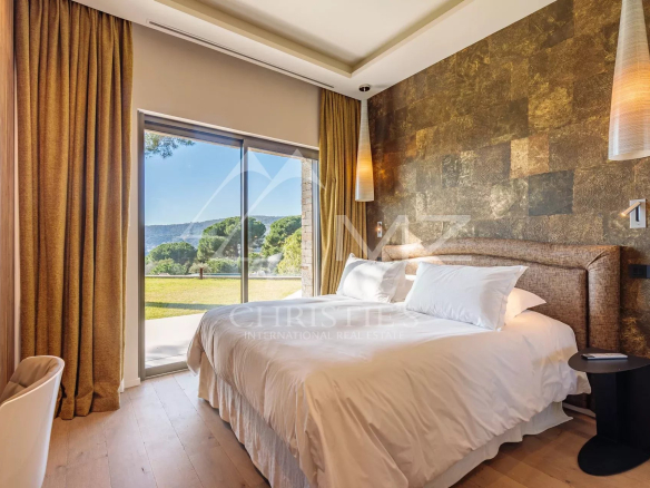 Chambre d'une villa moderne avec vue sur un jardin, fenêtres ouvertes, décoration élégante.