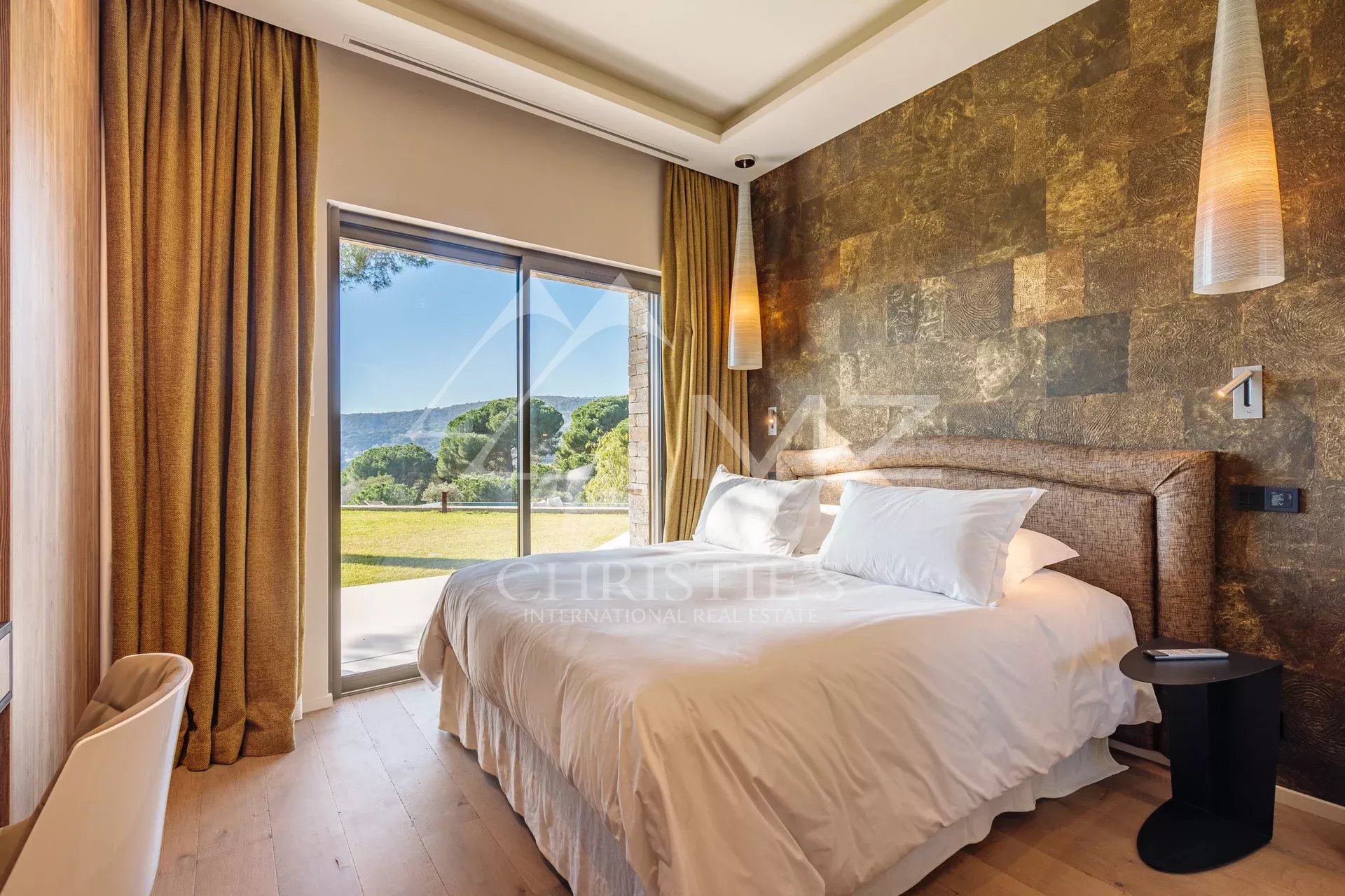 Chambre de villa à Ramatuelle Chambre d'une villa moderne avec vue sur un jardin, fenêtres ouvertes, décoration élégante.