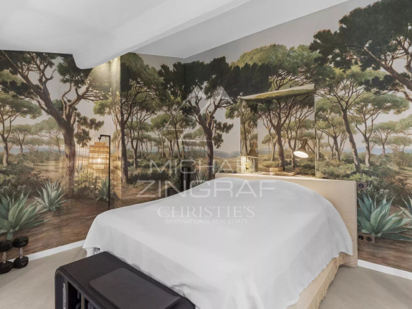 Chambre d'un duplex rénové avec un décor mural de paysage naturel.