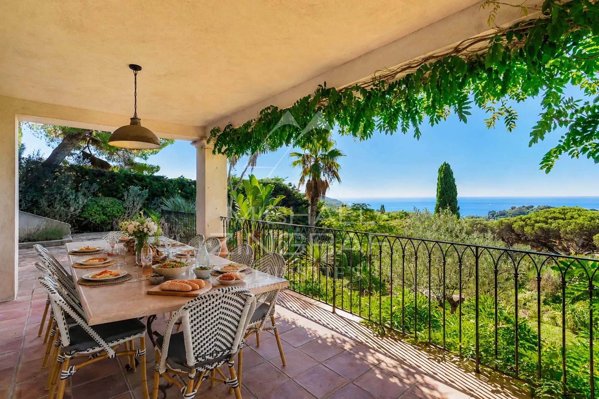 Terrace with sea view in La Croix-Valmer Terrace with set table offering a view of the sea and surrounding vegetation in La Croix-Valmer.