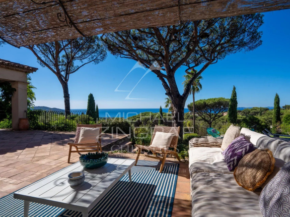 Terrace of a neo-Provençal villa with sea view in La Croix-Valmer, outdoor furniture and green landscape.
