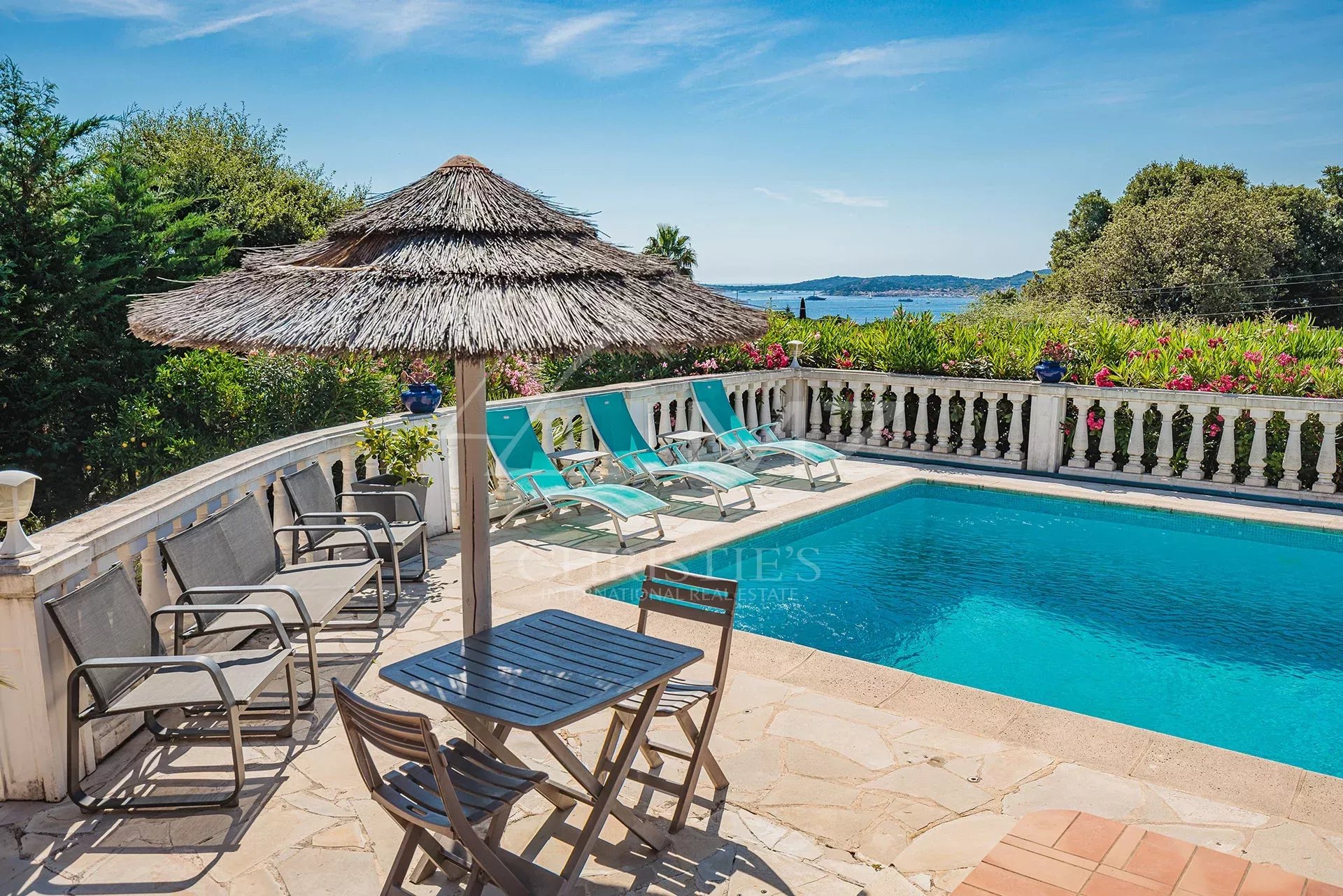 Villa provençale avec piscine à Grimaud Vue de la piscine et du jardin d'une villa provençale à Grimaud, avec vue sur la mer et le village de Saint-Tropez.